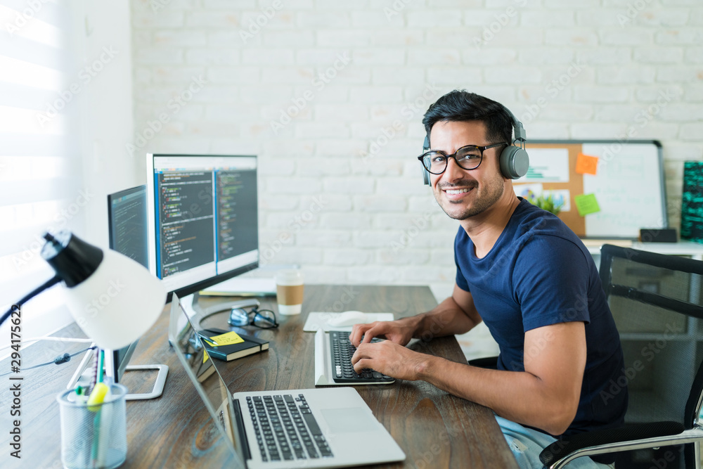 Wall mural confident hispanic software developer tying on keyboard