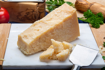 One piece of Italian original aged Parmesan cheese on white marble board close up