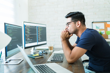 Attractive Male Coding On Computer At Desk