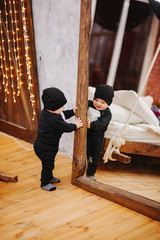 Vertical portrait of baby boy and big mirror. Beautiful little man celebrates New Year