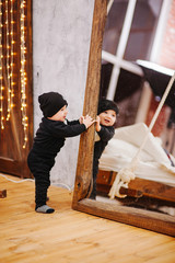 Vertical portrait of baby boy and big mirror. Beautiful little man celebrates New Year