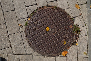 The metal hatch cover on  grey tile background
