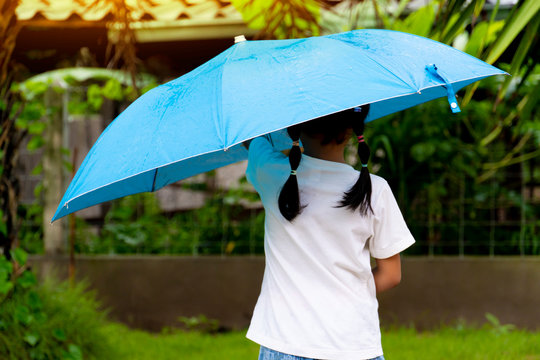 The girls wear white shirts, spread blue umbrellas in the backyard.