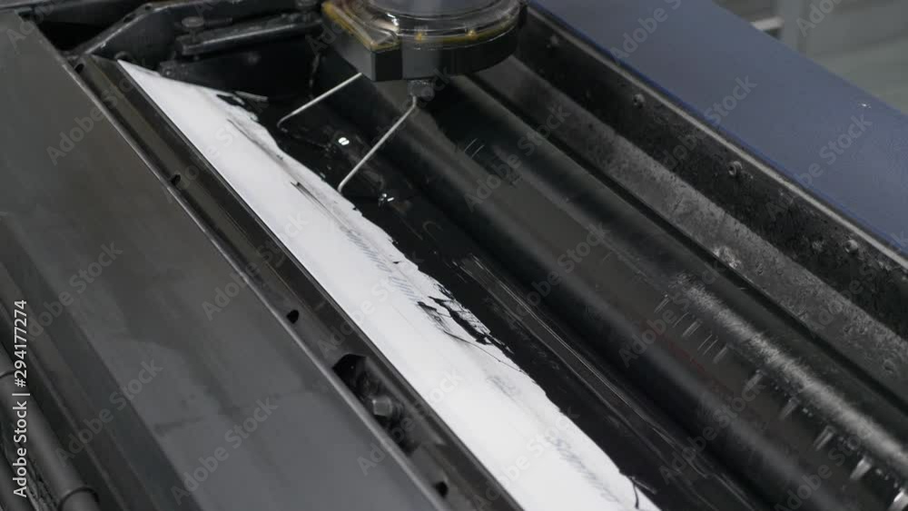 Poster a close up view from top of a printing machine at printing house showing the process of black ink be