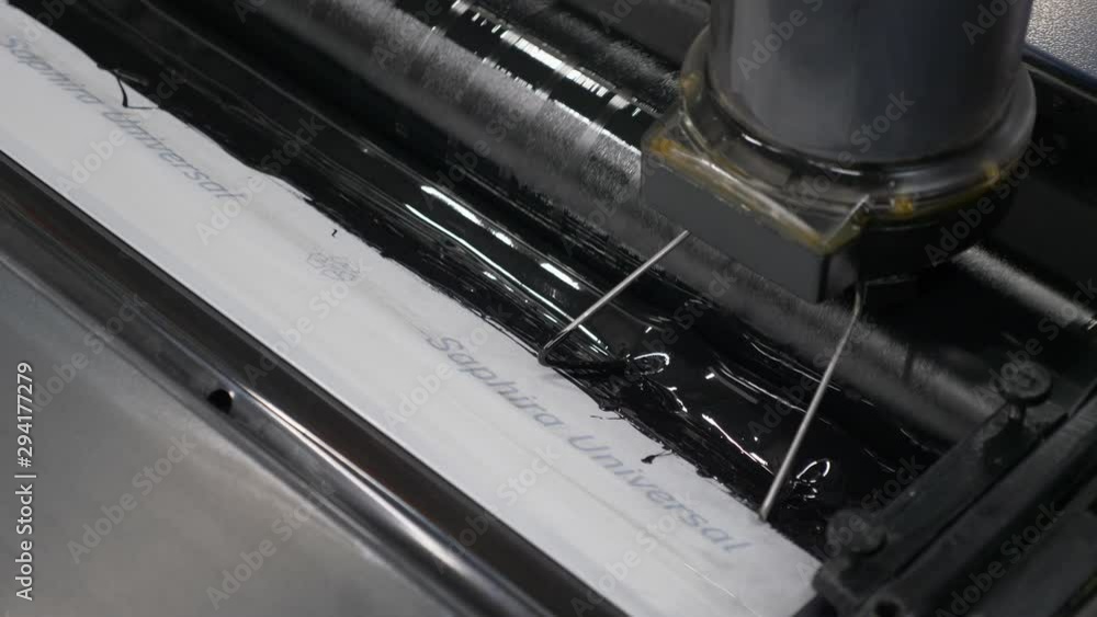 Poster a close up view from top of a printing machine at printing house showing the process of black ink be