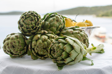 Obraz premium Bunch of fresh raw artichokes heads from artichoke plantation in Argolida, Greece ready to cook with lemon