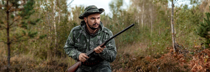 Hunter man in camouflage with a gun during the hunt in search of wild birds or game on the...