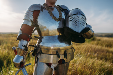 Knight in armor and helmet holds sword