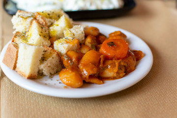 Greek food, cooked white beans with carrot and tomatoes served with roasted with olive oil and herbs bread