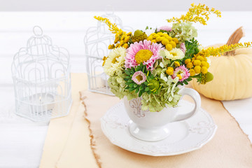 Woman shows how to make floral arrangement with summer flowers inside a ceramic cup