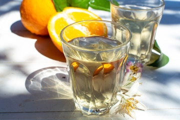 White wine served outside in garden on white table with fresh orange in sun lights