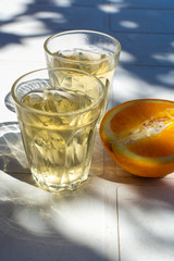 White wine served outside in garden on white table with fresh orange in sun lights