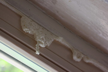 Fototapeta na wymiar Inaccurate apply a polyurethane foam on the old wooden window opening