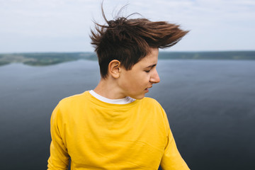 Stylish hipster teenager having fun and waving hair on top of rock mountain with amazing view on...