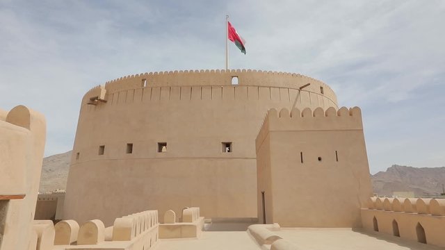Nizwa Fort, Oman - February 2019. Traditional Omani fortress, general plan and details, guns and a flag on the main tower.