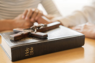 Christian woman praying with hands together on holy bible and wooden cross. Woman pray for god blessing to wishing have a better life and believe in goodness.