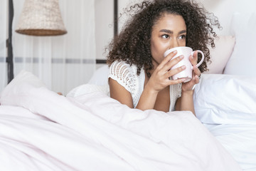 Amazing international girl drinking tea in her bed