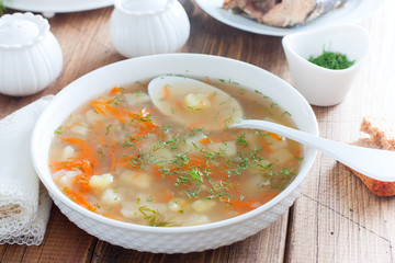 Ear from the head of pink salmon in a white bowl on a wooden table, selective focus