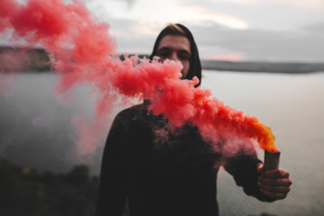 Red smoke bomb. Blurred image of ultras hooligan holding  smoke bomb in hand, standing on top of...