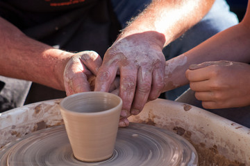 A potter craftsman transfers his skills to a student