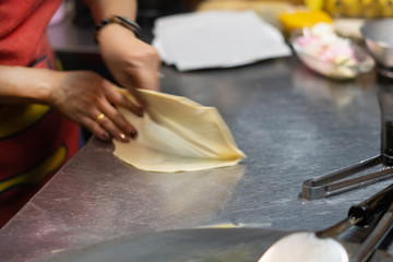 Thai woman cooking and selling traditional Thai sweet pancakes on the street of Khao Lak in Thailand.