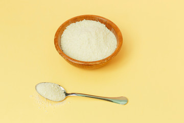 Collagen protein in the bowl and spoon - Hydrolyzed on yellow background