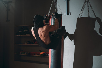 Hard workout exercises guy doing abs while holding with legs the boxing punching bag he all sweating have a intense workout
