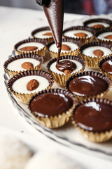 Chocolate ganache candy with almonds. Pouring chocolate, homemade dessert.