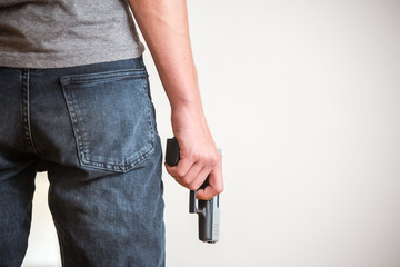 Man holding a gun in his hand with white background, rear view.