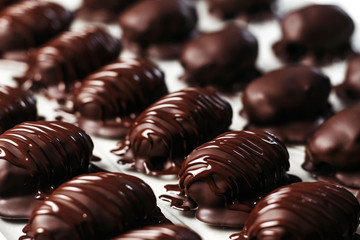 Dates in chocolate, dessert. Confectioner pours chocolate over dessert. Macro, close-up.