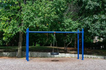 Blue Tire Swing at a Playground during the Summer with Green Trees