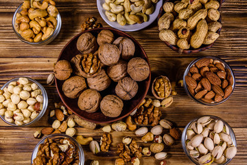 Various nuts (almond, cashew, hazelnut, pistachio, walnut) in bowls on a wooden table. Vegetarian meal. Healthy eating concept. Top view