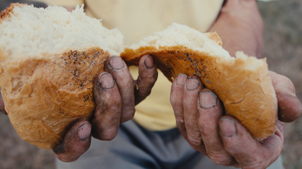 A loaf of bread in an old mans hands