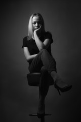 Obraz na płótnie Canvas Young womam sitting on chair in studio. Black and white