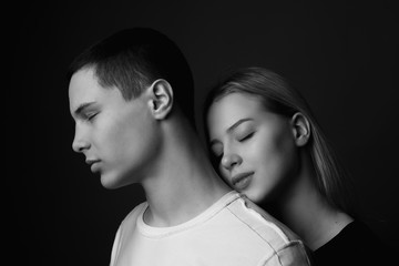 Young man and girl posing in studio. Black and white. Close up.