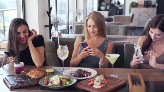 Group of young girls taking picture of their food during lunch together in fancy restaurant