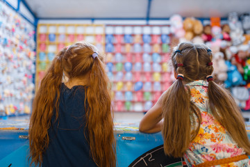 Two little girlfriends playing in shooting gallery