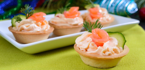 Tartlets with cream cheese and red salted salmon on a white plate for the festive table. Tasty portion light snack for a party. Finger Food.