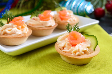 Tartlets with cream cheese and red salted salmon on a white plate for the festive table. Tasty portion light snack for a party. Finger Food.