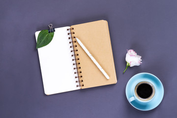 Morning coffee mug, empty notebook, pencil and white eustoma flower on dark table, cozy breakfast, top view, copy space