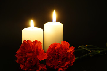 Two burning candles with flowers.