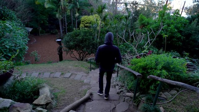 Man In A Hoody Walking Down A Set Of Flagstone Stairs In Wendy`s Secret Garden