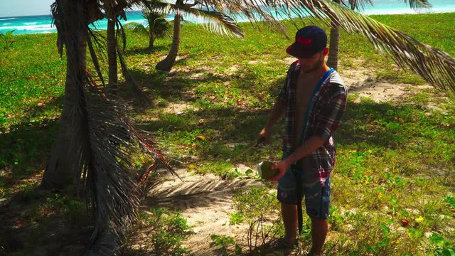 Opening a coconut on the beach wit a machete in the topical caribbean.