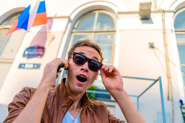 the guy is surprised by the conversation on the phone, against the background of the flag of Russia.