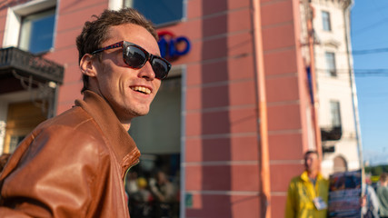 happy guy portrait walking in the summer city. with black glasses