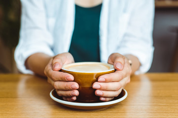 Drink coffee relax cosy photo with blurred background. Female hands holding mug of hot coffee in morning. Young woman relaxing coffee cup on hand. Good morning coffee or have a nice day 
