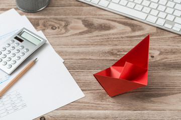 Top view office workspace with red paper ship
