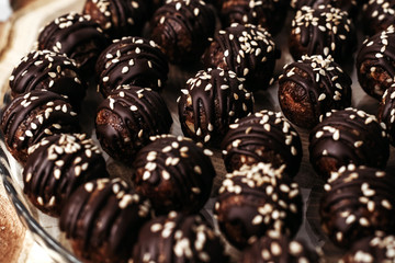 Round chocolates candy with sesame seeds. Dark background, luxury dessert, dark chocolate, handmade.