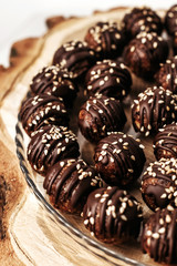 Round chocolates candy with sesame seeds. Dark background, luxury dessert, dark chocolate, handmade.