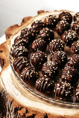 Round chocolates candy with sesame seeds. Dark background, luxury dessert, dark chocolate, handmade. View from above.